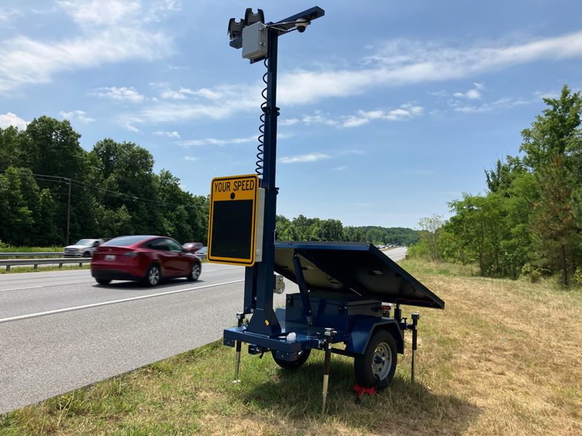 Blue speed enforcement trailer with solar panels next to a road with traffic in Prince George's County, Maryland, USA