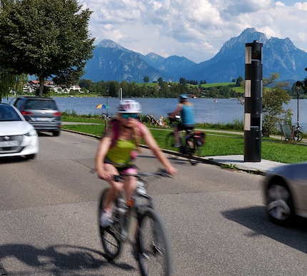 A road at the lake with car traffic, cyclists and pedestrians
